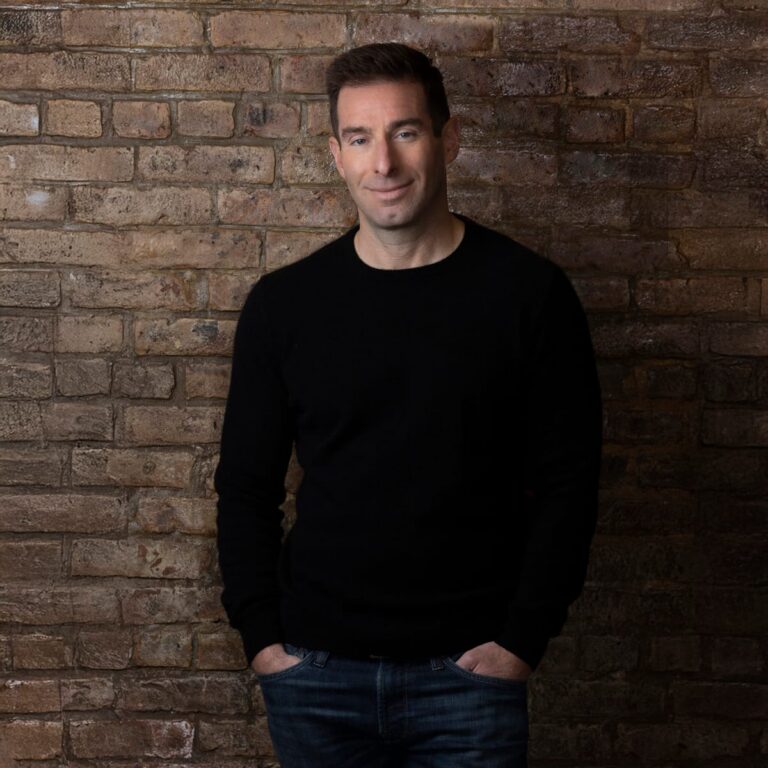 Branding portrait of a business owner in a black sweater against a brick wall