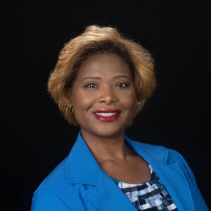Corporate headshot of a woman in a blue blazer on a black backdrop