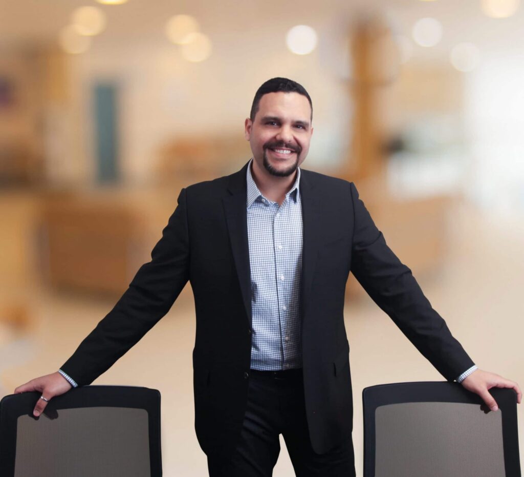Executive portrait of a business owner leaning on conference chairs in a softly lit office