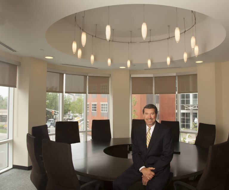 Executive seated in a round conference room with pendant lights