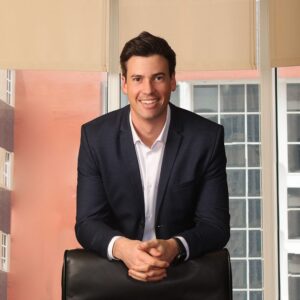 Executive portrait of a man seated by tall office windows