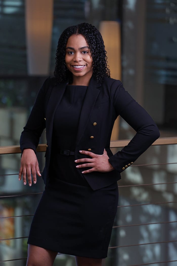 Executive portrait of a woman standing in a modern glass office atrium