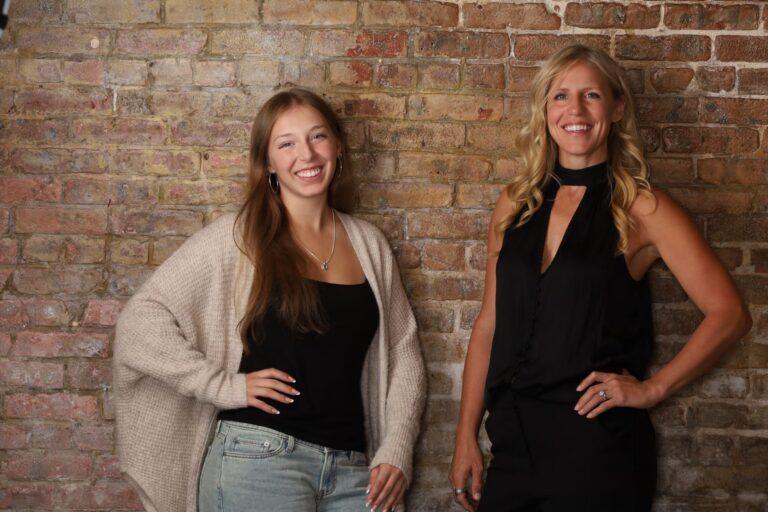 Two women photographed together in front of the brick wall at the Five Star SEO studio in Freehold, NJ